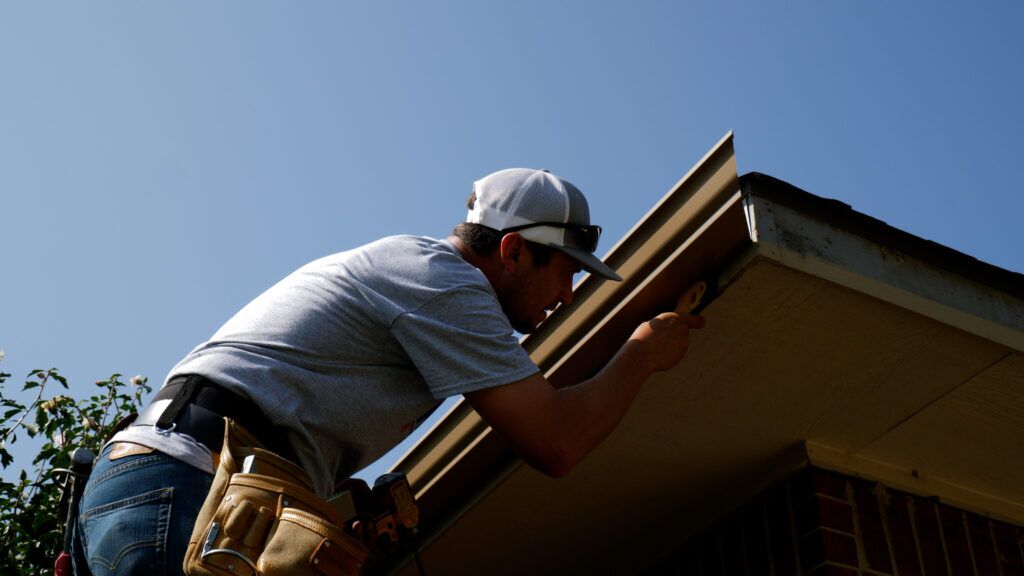 Seamless gutters leveled at installation on the eaves of a house.
