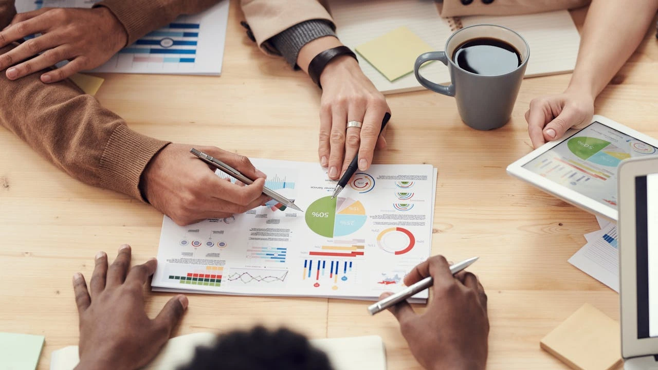 Members of an operations team make observations on visual data on a conference room table.