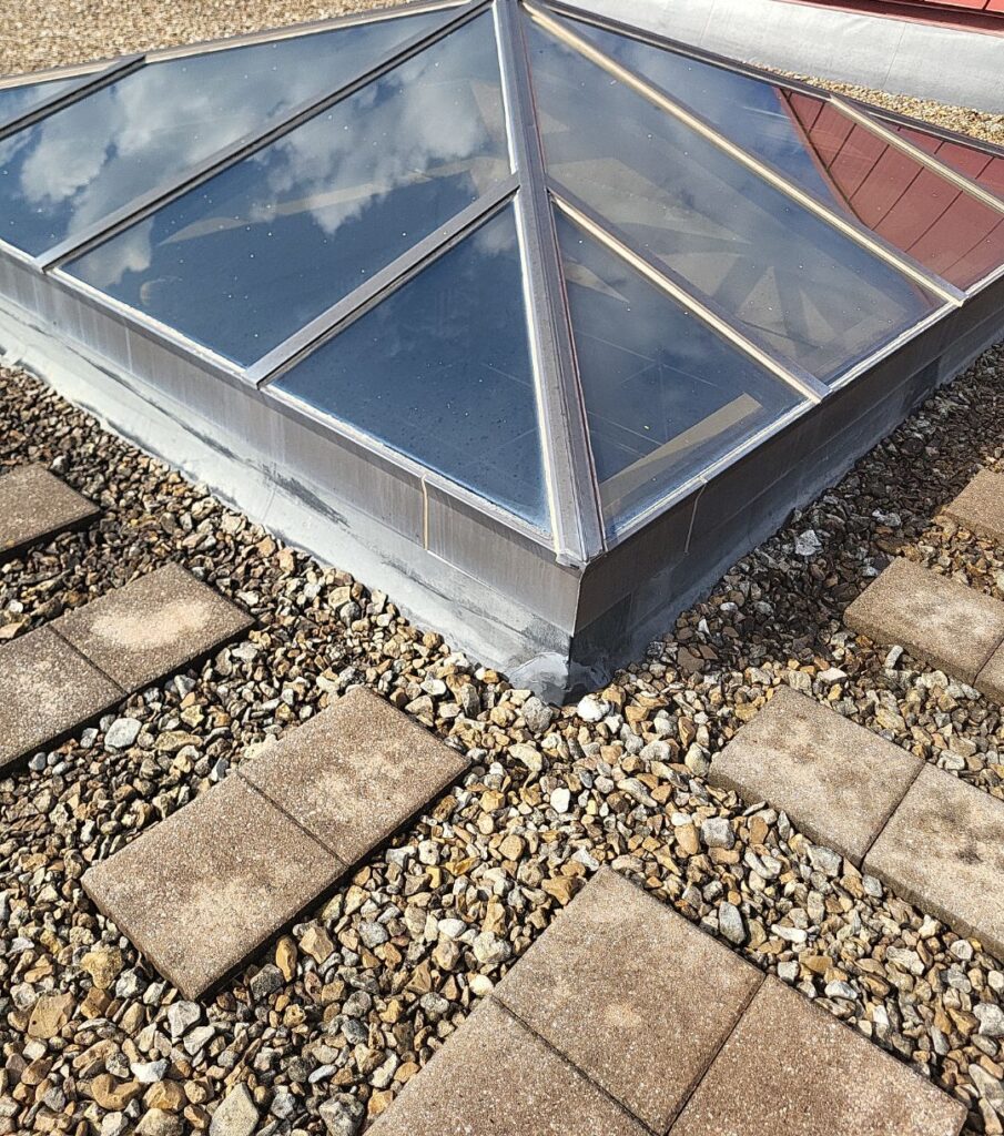 Ballast surrounds a skylight on a low slope roof. Paving stones allow for foot traffic without interfering with the membrane beneath the ballast.