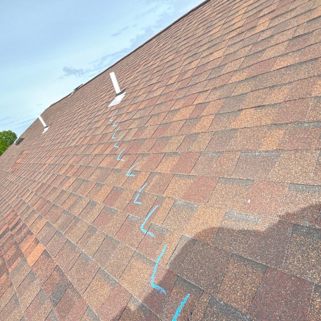 Zippering caused by mixing discontinued shingles with new shingles, outlined in chalk..