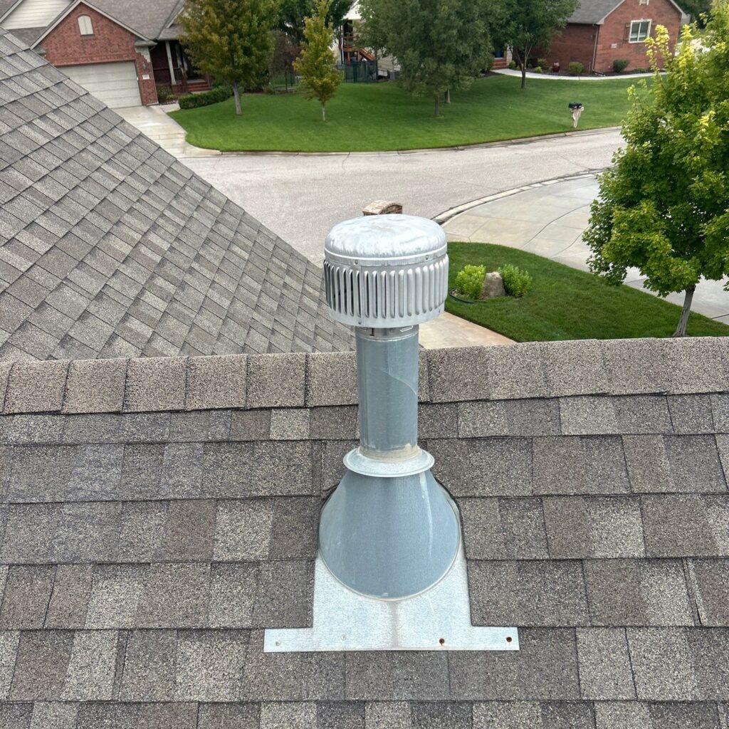 5–10-year-old heater flue flashing with dried sealant, dented cap, and exposed fasteners.