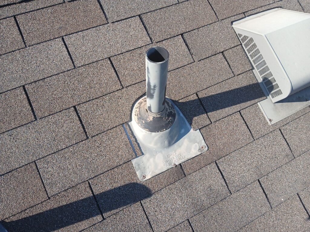 White pipe boot with exposed fasteners, deformed metal, and discoloration.