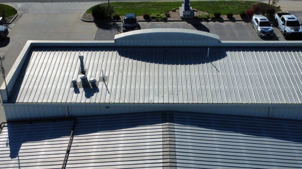 A commercial building with a metal roof and multiple exhaust vents at the front of the building.