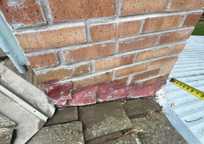 Deteriorated counterflashing on a wood shake roof with a brick chimney.