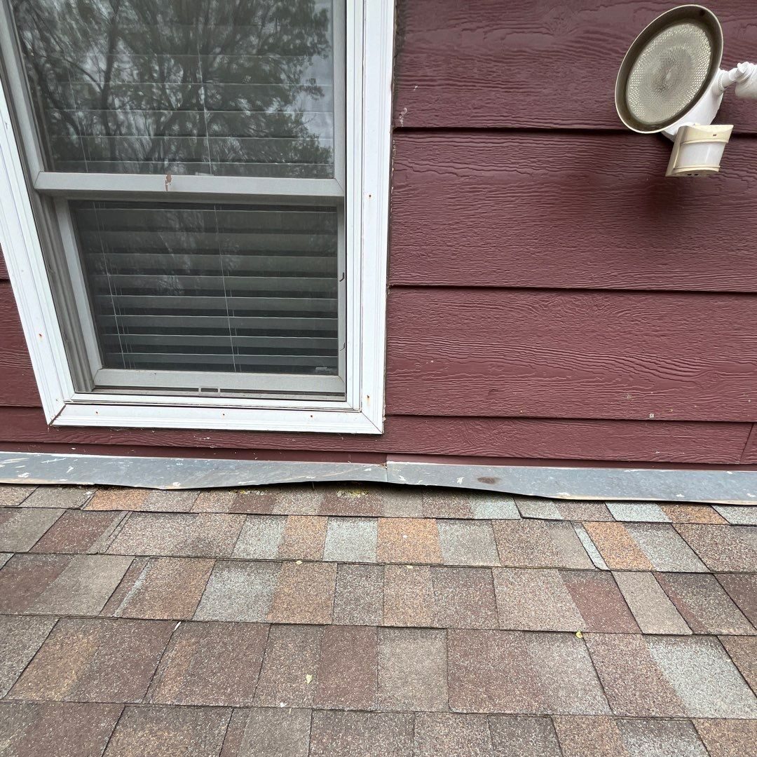 Headwall flashing at a roof-to-wall transition with backed out fasteners that produced warped metal, compromising the flashing.