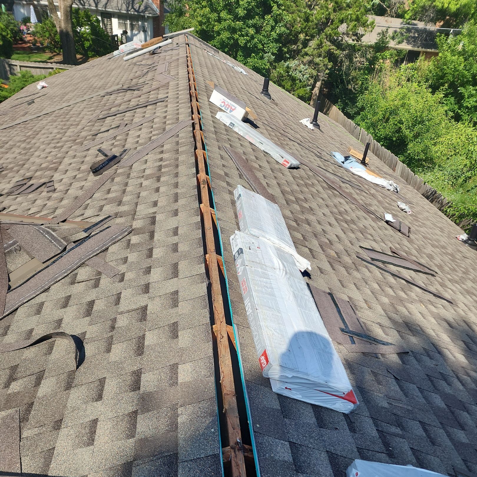 An open slot for a ridge vent on an asphalt shingle roof with an exposed ridge board.