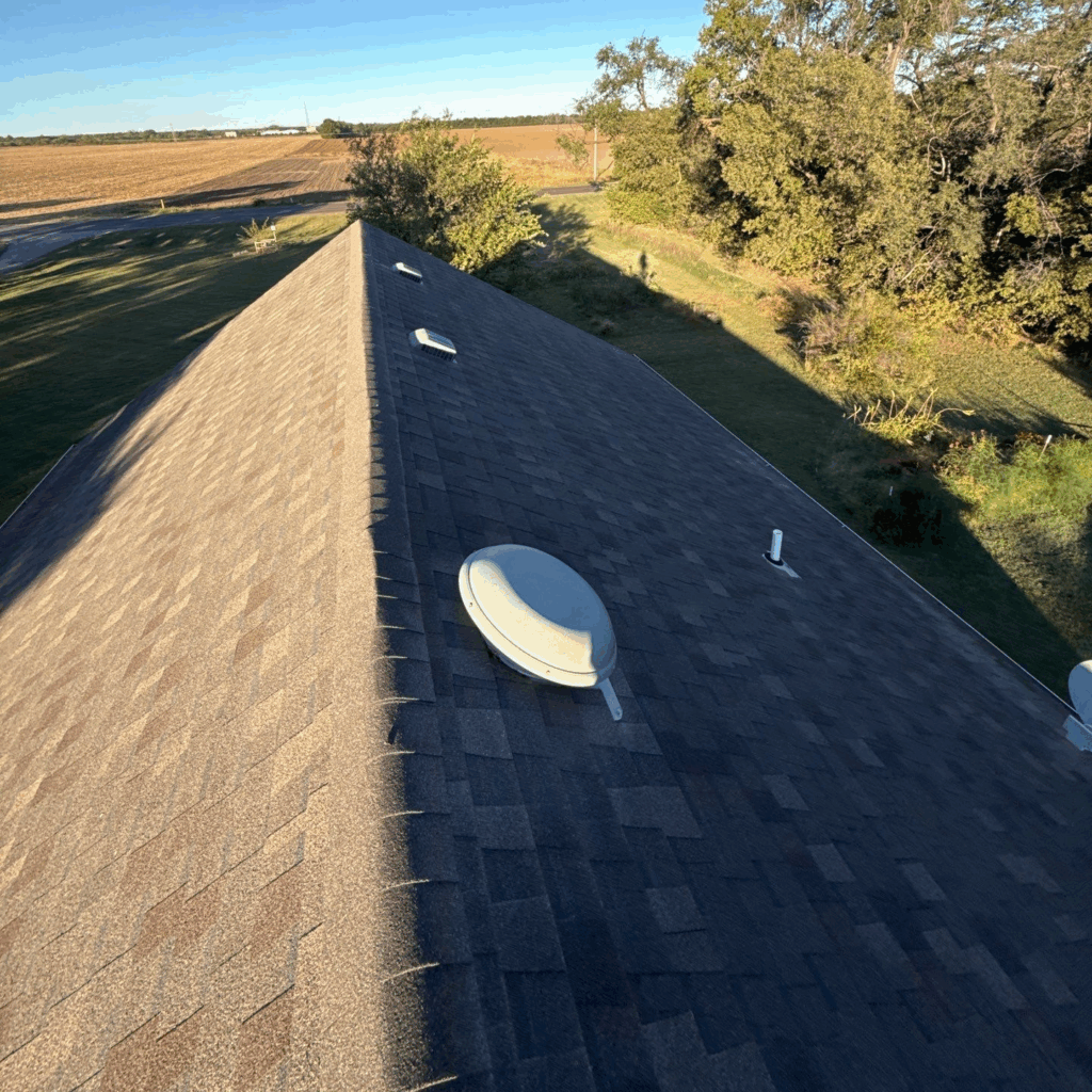 An asphalt shingle roof with mixed exhaust ventilation methods -- both box vents and a powered attic fan can short-circuit the ventilation system.