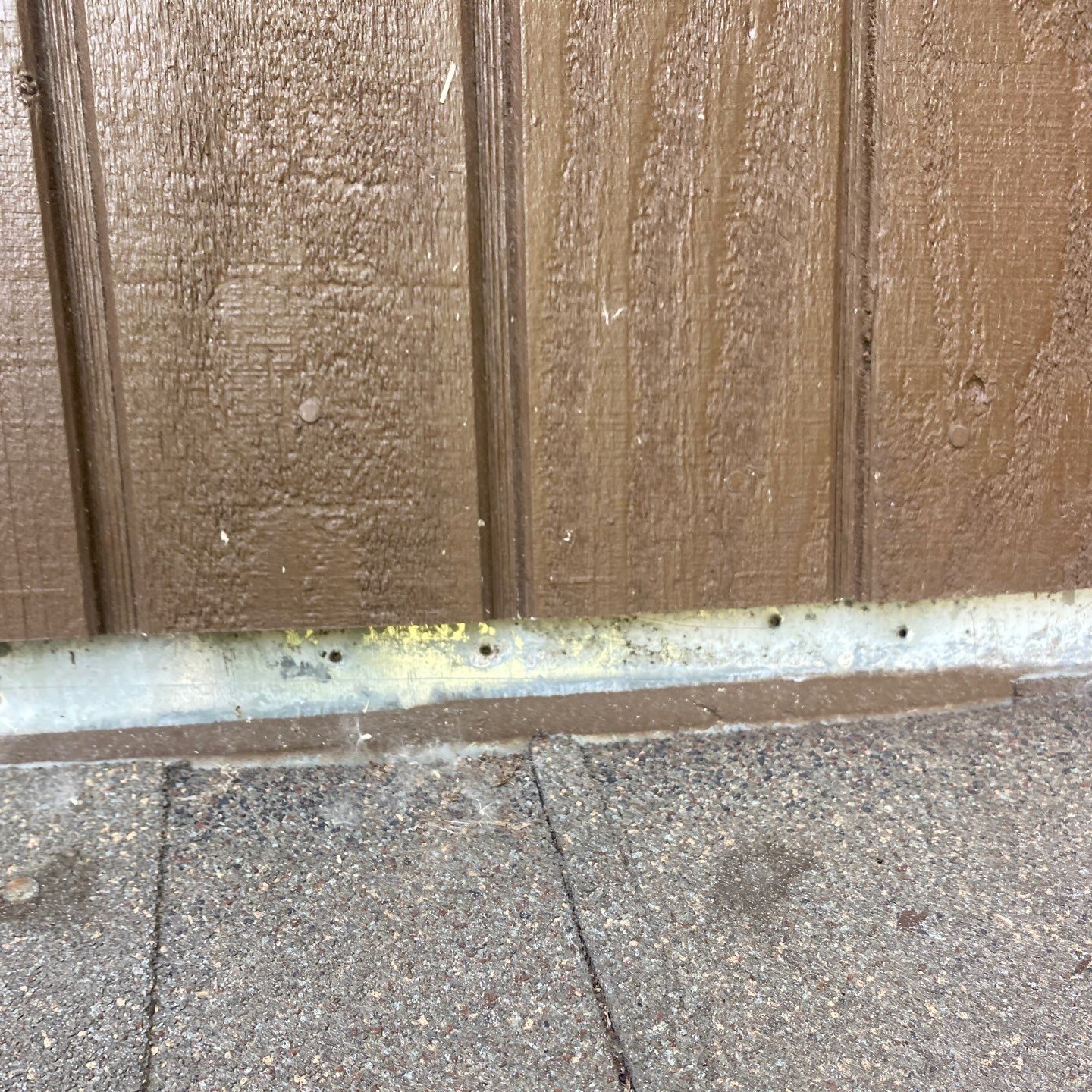 The vertical leg on this headwall flashing has visible holes and was shingled over with field shingles, signs of poor installation.