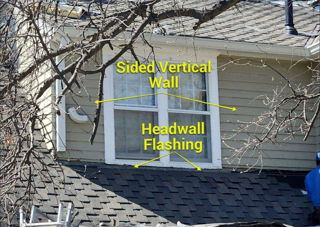 A vertical wall on an asphalt shingle roof during a reroof with exposed headwall flashing.