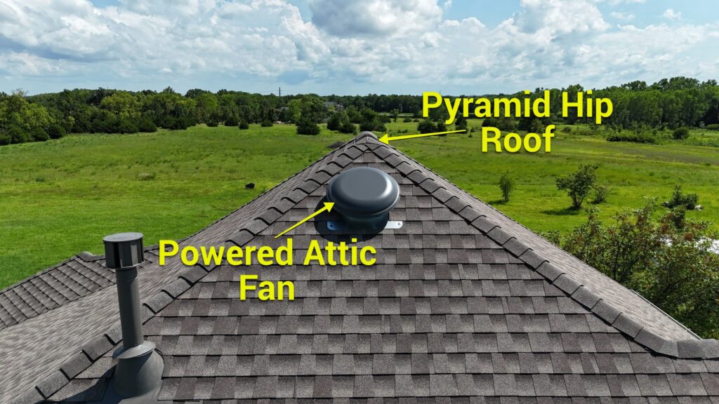 An annotated picture of a roof-mounted powered attic fan placed near the ridge on a steep pyramid hip roof.