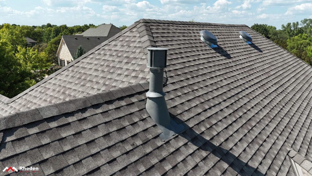 Two powered attic fans on a residential asphalt shingle roof with a large attic space.