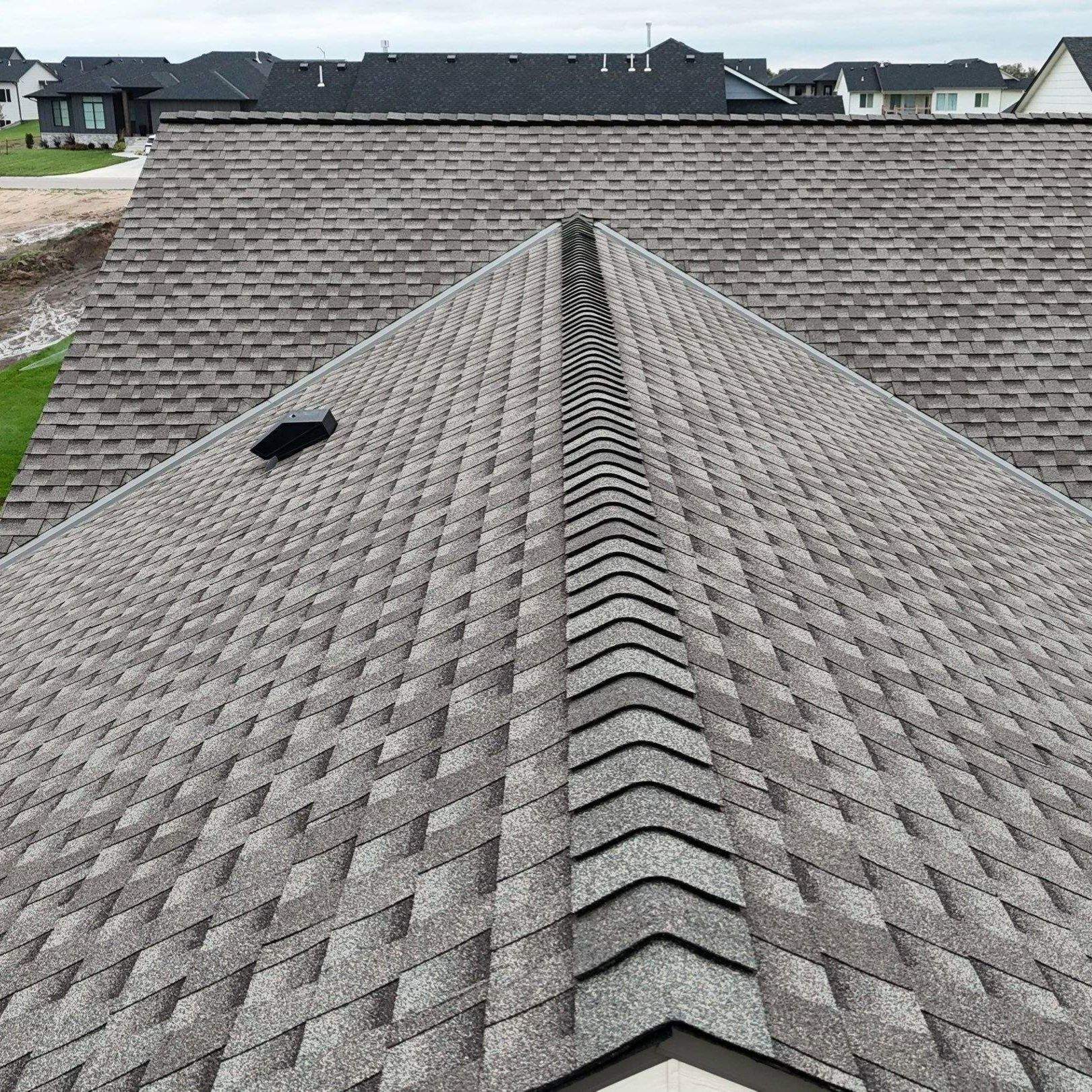 High profile ridge caps with ridge vent, a powered bathroom vent, and open valleys in the background.