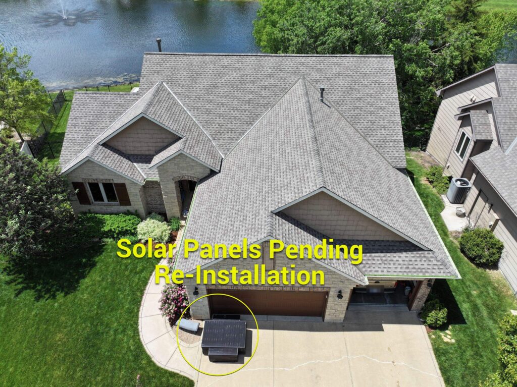 Annotated photo after an asphalt shingle roof replacement with solar panels in the driveway until they can be reinstalled by the original installers.