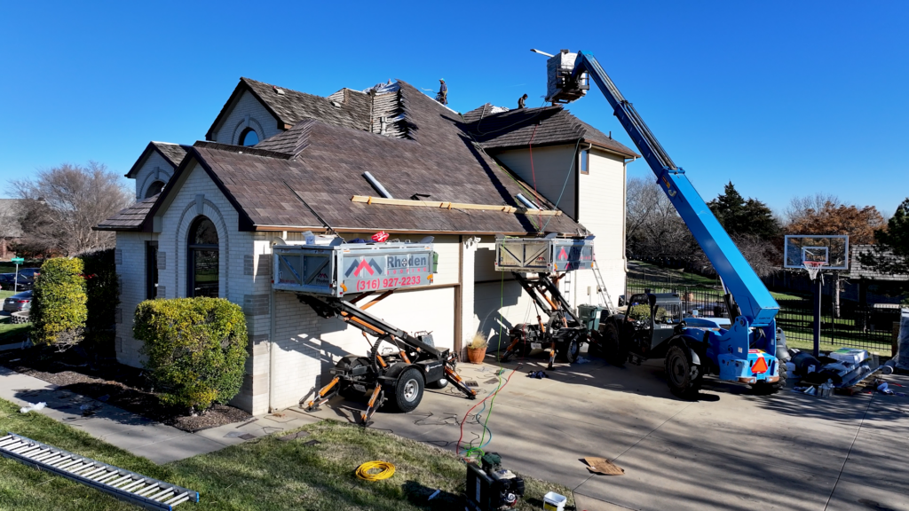 Two Equipters and a telehandler assist with loading material and managing debris on a steep-slope residential DaVinci roof.