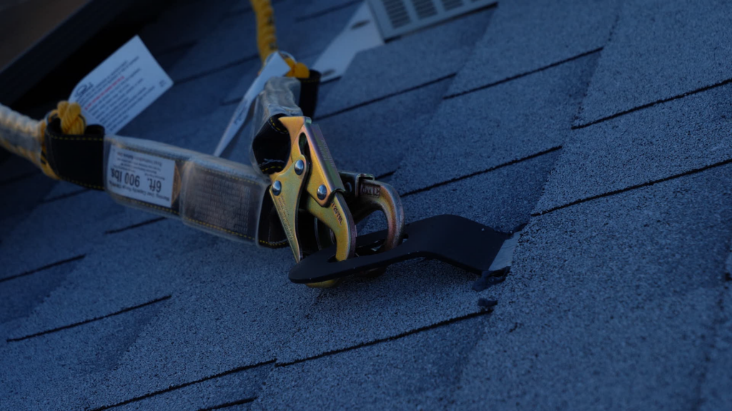 A harness attached to a roof jack on a residential asphalt shingle roof.