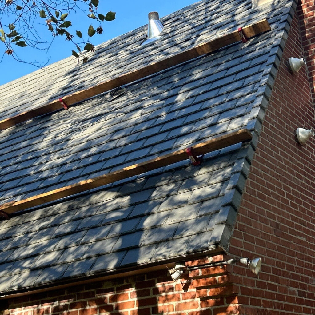 A brick home with a DaVinci tile roof and a steep, 12:12 pitch that requires roof jacks and planks.