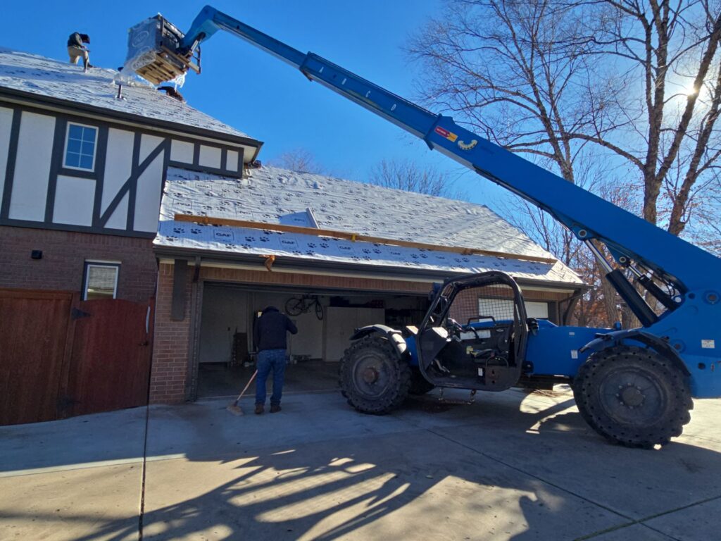 A telehandler loading material on a stripped specialty tile roof.