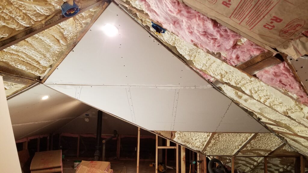 Finished sloped ceiling over a hot roof, with a small cavity between closed-cell spray foam and drywall filled with fiberglass for sound control.