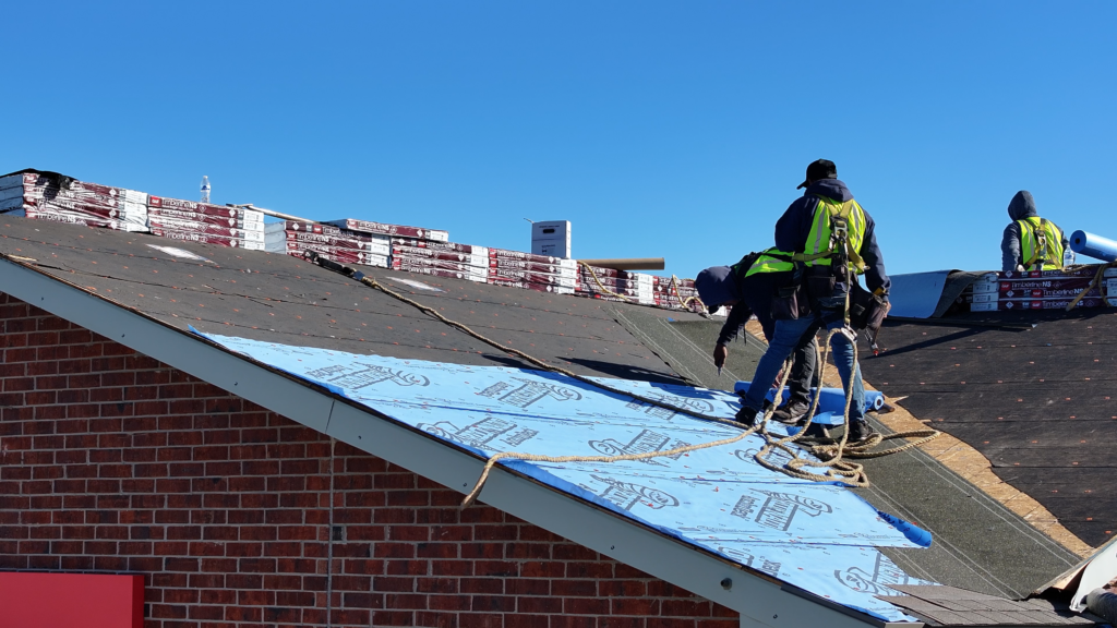 Roofnado underlayment installed from one end of the rake to the metal valley by two workers.