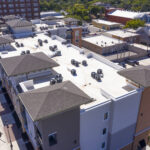 A low-slope roof system paired with a steep-slope shingle accent on a four-story commercial building.