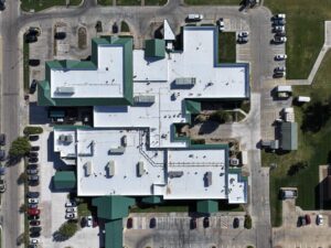 A hospital with a new, white TPO membrane, multiple roof-mounted units and green edge metals.