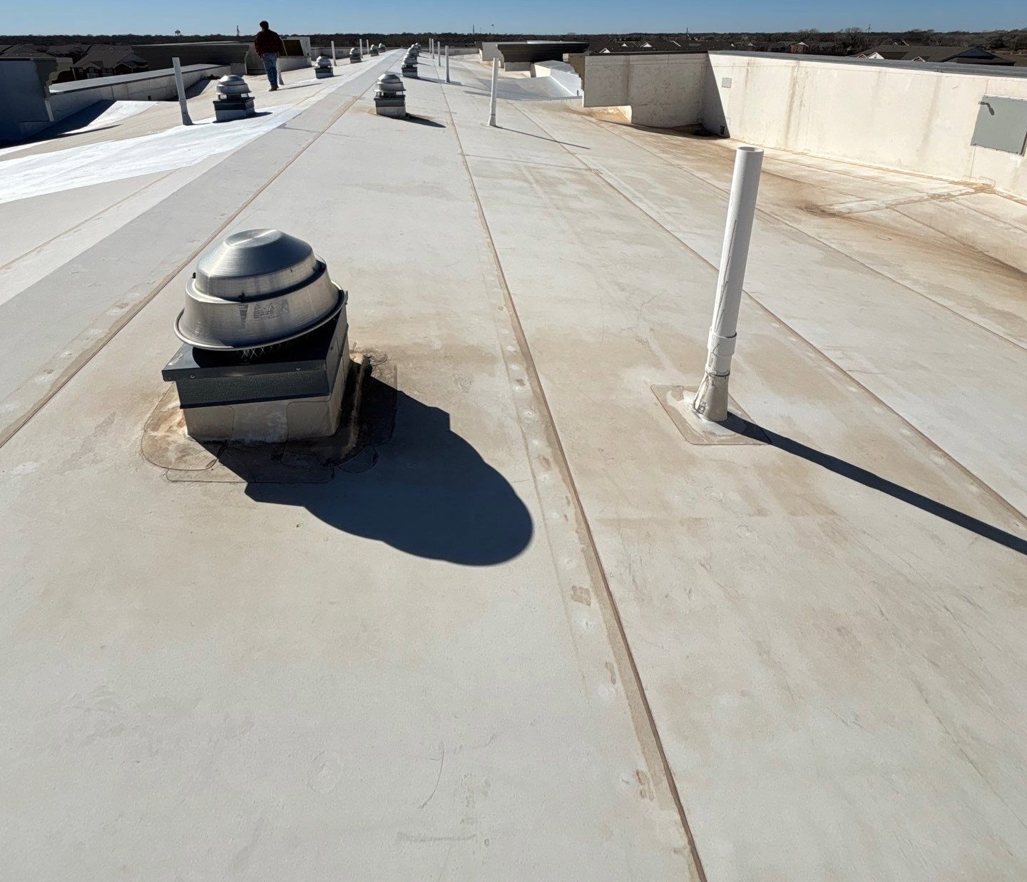 Structural sleep on a low-slope PVC roof with curbs and pipe penetrations.