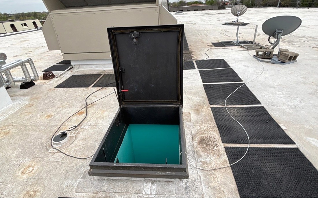 Low-Slope Roof Hatch with Walkway Pads A low-slope commercial membrane roof with an open roof hatch andwalkway pads to an HVAC unit.