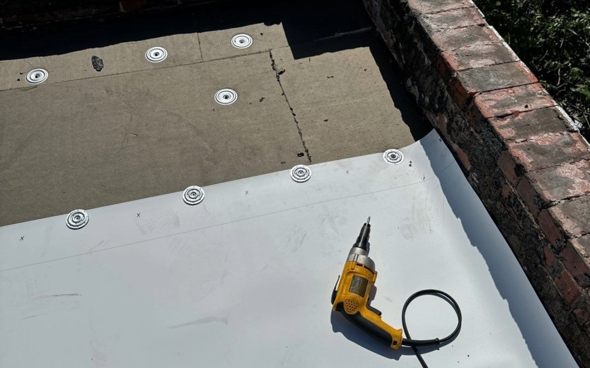 Mechanical fasteners securing insulation and TPO membrane to the roof deck of a low-slope commercial roof.