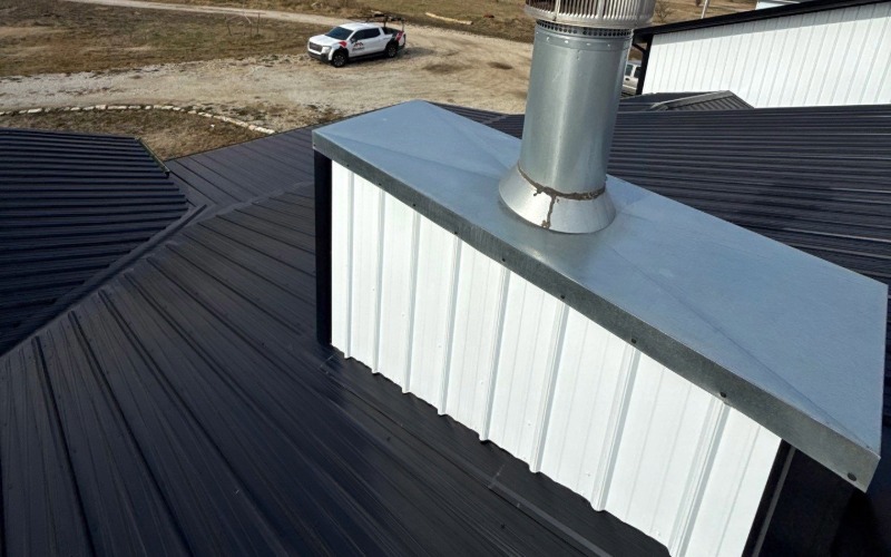 A black metal roof with a metal cladded chimney with a new chimney chase.