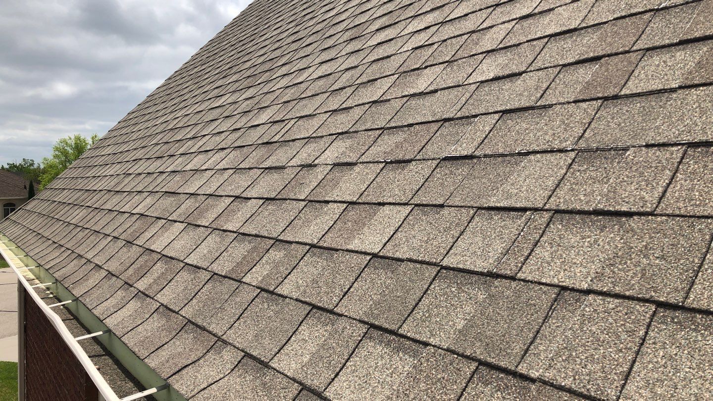 Very Steep Asphalt Shingle at Eaves Eave of a steep asphalt shingle roof with degranulation visible in the gutters.